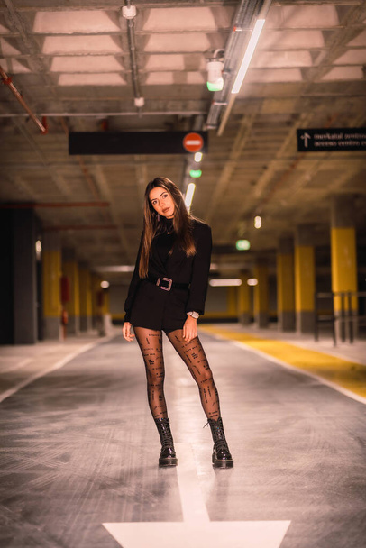 Young caucasian model with black jacket posing in an empty underground car park. Night urban session in the city - Foto, Bild