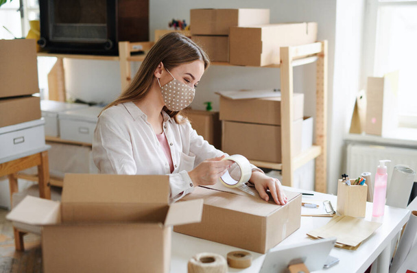 Woman dropshipper working at home, packing parcels. Coronavirus concept. - Foto, imagen