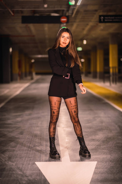 Young caucasian model with black jacket posing in an empty underground car park. Night urban session in the city - Fotografie, Obrázek