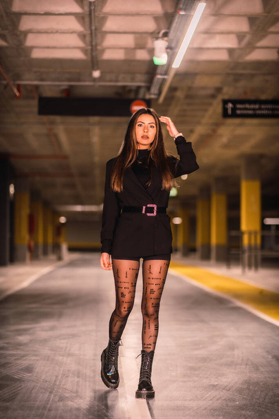 Young caucasian model with black jacket posing in an empty underground car park. Night urban session in the city - Photo, image