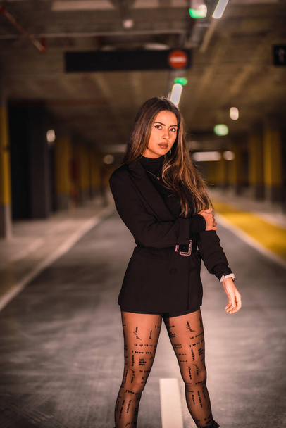 Young caucasian model with black jacket posing in an empty underground car park. Night urban session in the city - 写真・画像