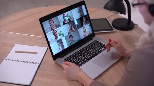 Женщина в видеочате с коллегами на ноутбуке в офисе, крупный план - Кадры, видео