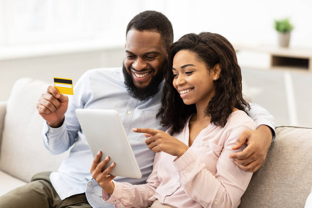Черная пара с помощью планшета и дебетовой кредитной карты дома - Фото, изображение