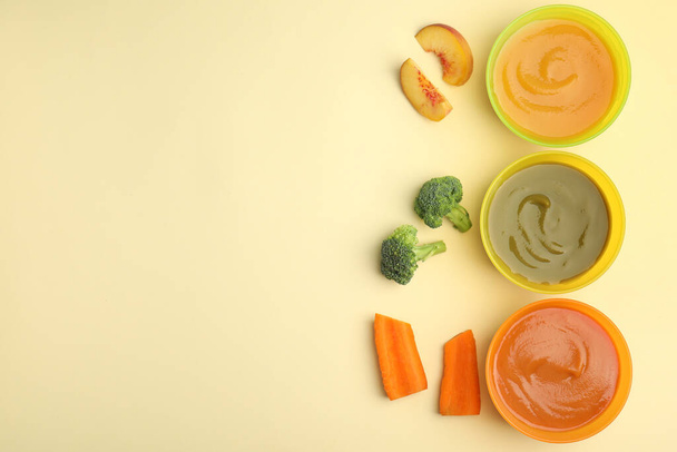Baby food in bowls and fresh ingredients on yellow background, flat lay. Space for text - Foto, Imagem