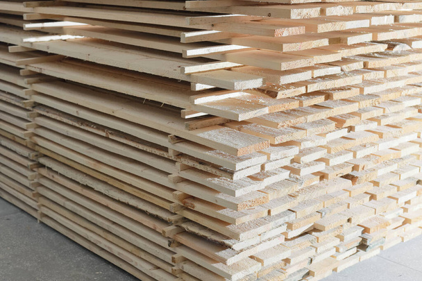 Wooden boards are stacked in a sawmill or carpentry shop. Drying and marketing of wood. - Photo, Image