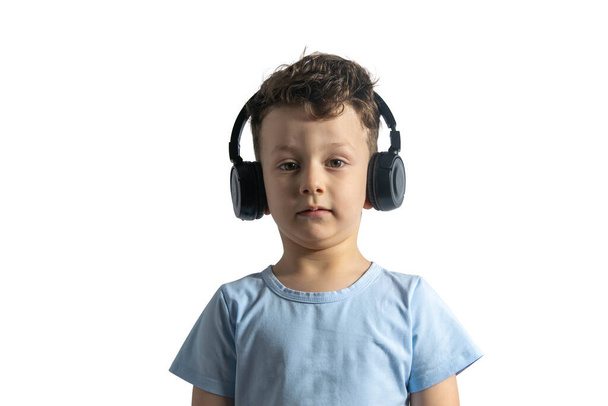 Kaunis eurooppalainen poika kuuntelee musiikkia kuulokkeilla. Musiikin ystävä lapsuudesta lähtien. DJ. Eristetty valkoisella pohjalla - Valokuva, kuva