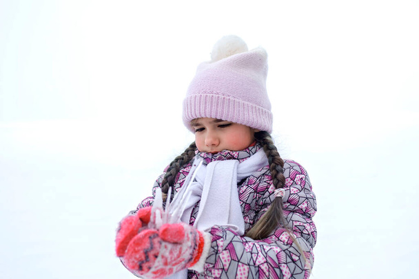 Girl gathering a winter bunch of icicles and taste them, seasonal outdoor activities, lifestyle - Photo, Image