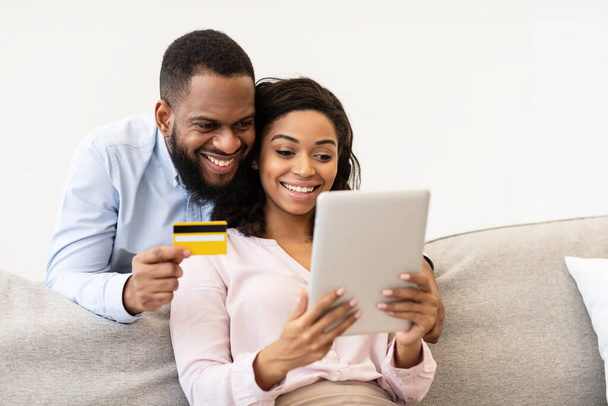 Siyah çift evde tablet ve banka kartı kullanıyor. - Fotoğraf, Görsel