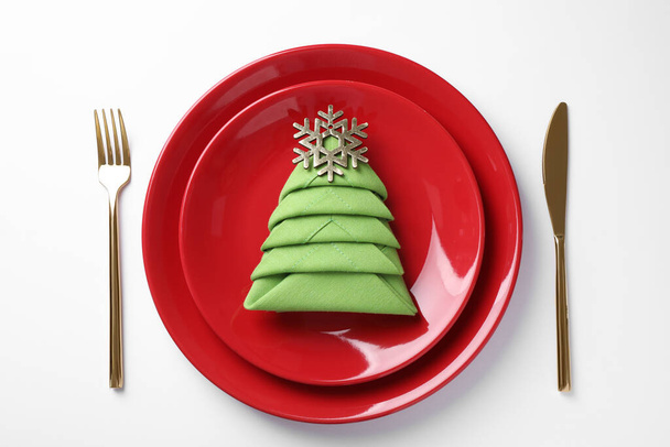 Festive table setting with green napkin folded in shape of Christmas tree on white background, top view - Фото, изображение