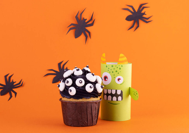 funny paper monster with a scary cupcake on an orange background with black spiders. background for Halloween - 写真・画像
