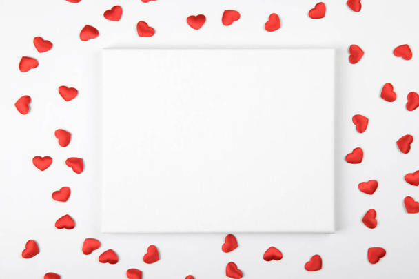 Vászon mockup piros szívvel és ünnepi dekorációs szalaggal fehér alapon. Design elem Valentin-napra és anyák napjára gratulálok, köszönöm, üdvözlő vagy meghívó kártya, művészeti munka - Fotó, kép