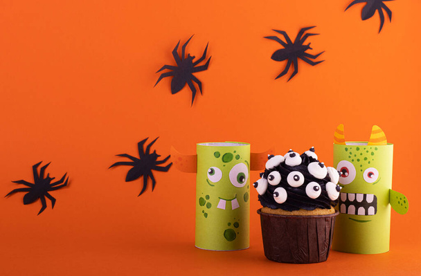 funny paper monster with a scary cupcake on an orange background with black spiders. background for Halloween - 写真・画像