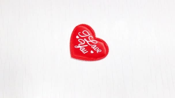 Dekoratives rotes Herz auf weißem Holzgrund und die Inschrift I love you. Symbol für den Valentinstag. Kopierraum. Ansicht von oben. - Filmmaterial, Video