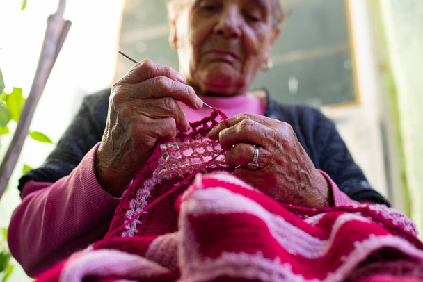 Old woman knitting at home in the evening. - Photo, Image