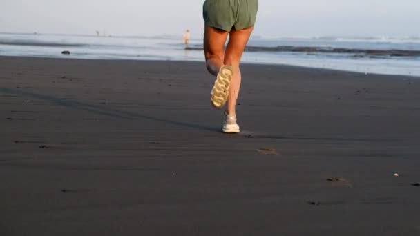 αθλητικά πόδια σε αθλητικά παπούτσια κατά μήκος της παραλίας, βρεγμένα παπούτσια, υπαίθρια προπόνηση - Πλάνα, βίντεο
