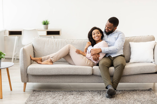 Afrikanisches Paar verbringt Wochenende zusammen auf Couch liegend - Foto, Bild