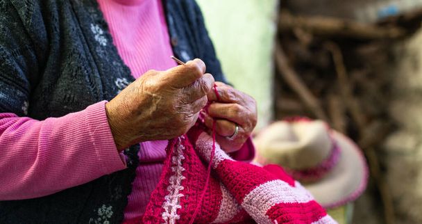 Vecchia donna che lavora a maglia a casa la sera. - Foto, immagini