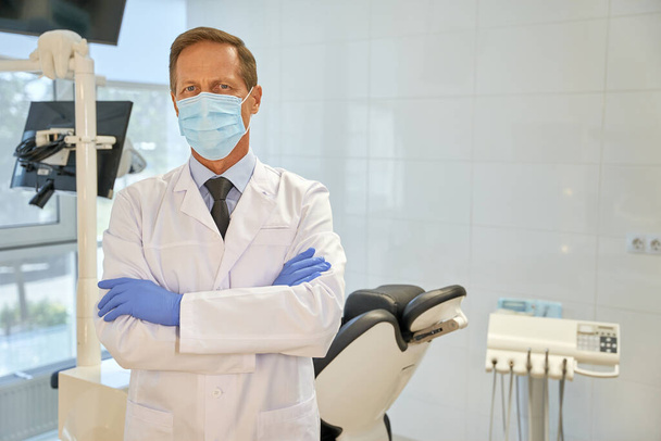 Mężczyzna dentysta w mundurze pozował w klinice - Zdjęcie, obraz