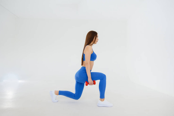 Sexy young girl performs sports exercises on a white background. Fitness, healthy lifestyle - Foto, afbeelding