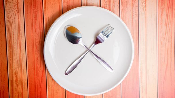 Set di piatti vuoti in ceramica (piatto), cucchiai e forchette isolati su fondo di legno. Posa piatta, vista dall'alto. Stile minimale. - Foto, immagini
