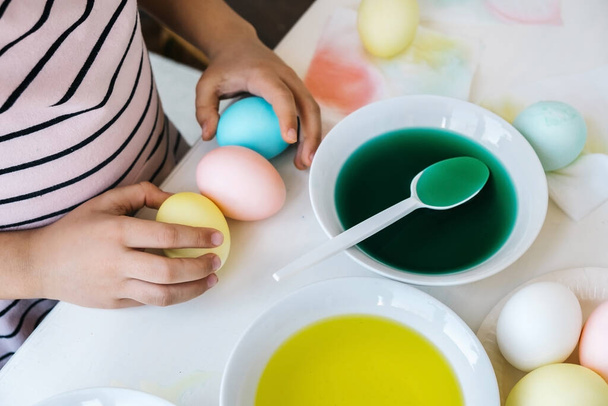 Easter preparation concept. Close up child hands taking colorful dyes eggs. Coloring Easter eggs. - 写真・画像