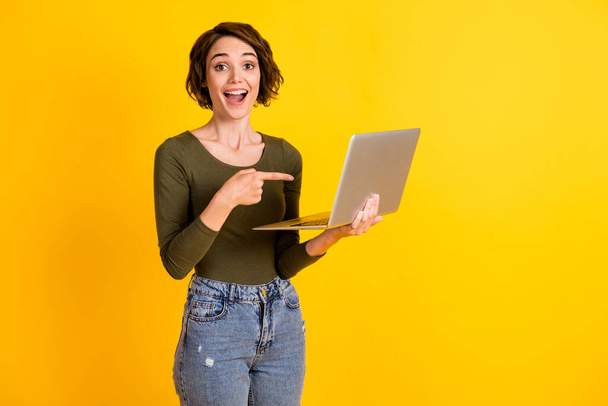 Positive lady point index finger laptop choose decide promotion concept wear sweater denim isolated on shine yellow color background - Foto, Imagem