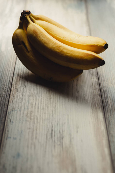 Reife Bananen auf rustikalem Holzgrund, Kopierraum links - Foto, Bild