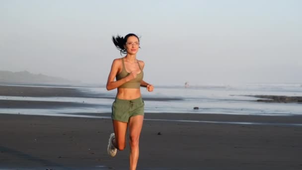 νεαρή γυμνάστρια τρέχει στην παραλία της ανατολής - Πλάνα, βίντεο