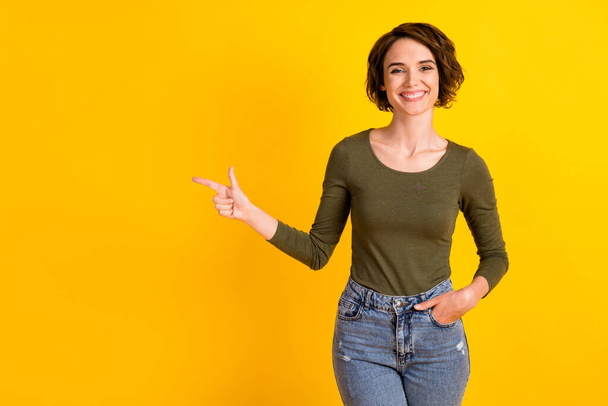 Photo of positive girl point index finger empty space for ads promotion isolated on bright yellow color background - Foto, immagini