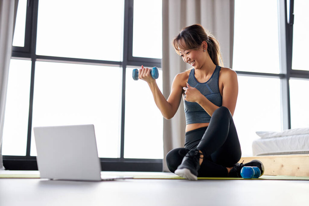 online training. fit young asian woman excercising at home, watching video tutorial on laptop - Foto, Bild