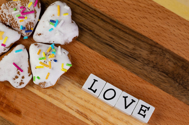 Een compositie van geglazuurde peperkoek in de vorm van harten en het woord "Love" op een houten plank - Foto, afbeelding