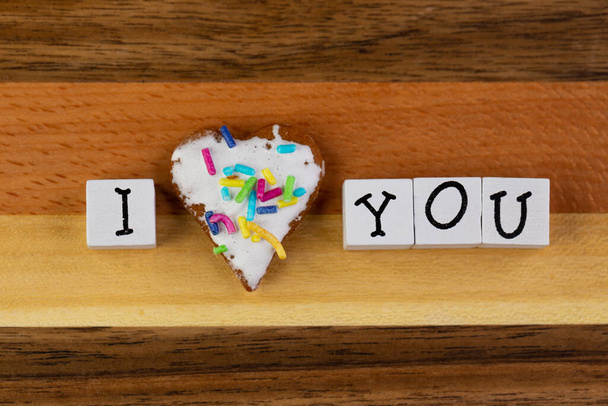 Een compositie van geglazuurde peperkoek in de vorm van harten en de zin "I Love You" gearrangeerd op een houten plank - Foto, afbeelding