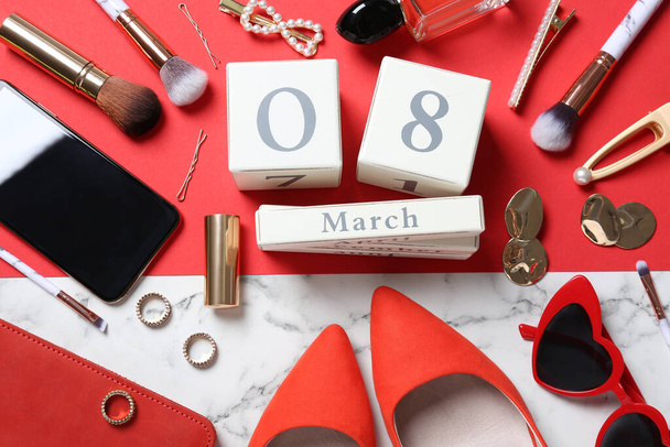 Flat lay composition with wooden block calendar, smartphone and women's accessories on color background. 8th of March celebration - Foto, Imagen