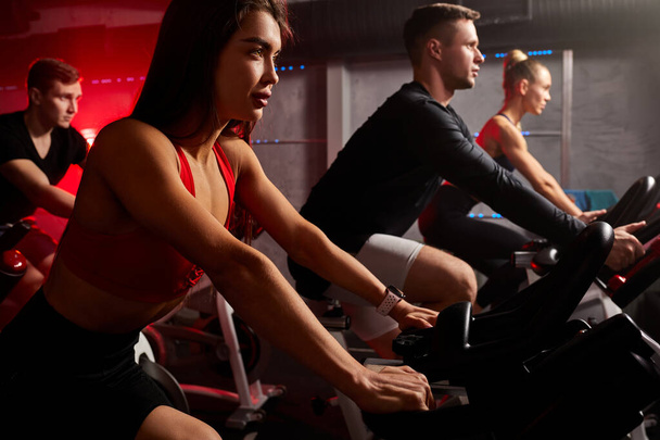 fitness together on bicycles. young friends pedal on a stationary bike at the gym - Фото, зображення