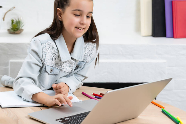 παιδιά, εκπαίδευση και μακρινή έννοια μάθησης, κοριτσάκι φοιτητής με φορητό υπολογιστή στο σπίτι - Φωτογραφία, εικόνα