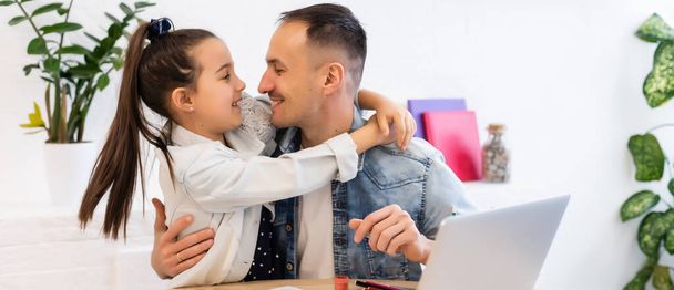 Genç baba, anaokulu kızına birlikte ders çalışmasında yardım ediyor. Bilgisayarda ders izliyorlar, baba ve kız evde öğreniyor, internet dersinde karantinada. - Fotoğraf, Görsel