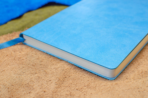 Un diario de papel en una cubierta de cuero azul con un marcador. En piezas de cuero multicolor - Foto, imagen