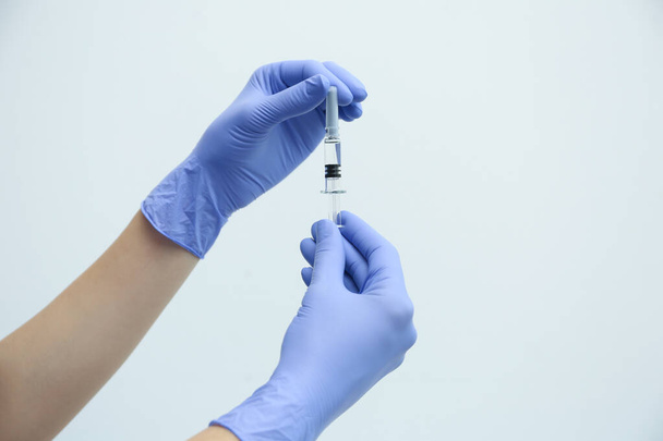 Doctor holding syringe with COVID-19 vaccine on light background, closeup - Zdjęcie, obraz
