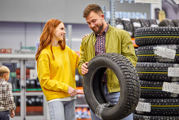 adorable woman and handsome man choose tire for their first car - Φωτογραφία, εικόνα