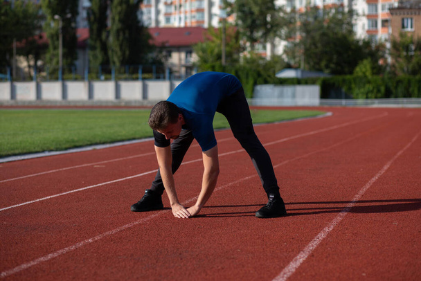 Fit vousatý muž se zahřeje před cvičením na stadionu. Mezera pro text - Fotografie, Obrázek
