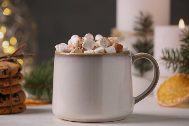 Cup of hot drink with marshmallows on white table, closeup - 写真・画像