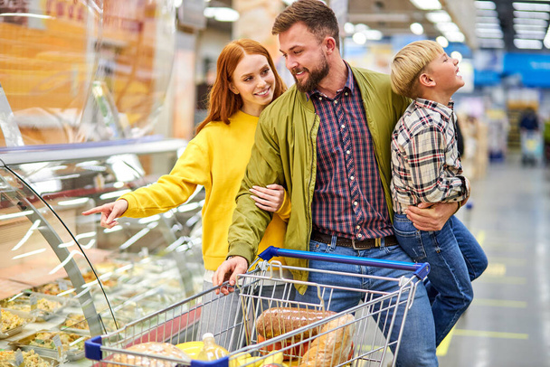 cheerful couple, parents with restless son in grocery store - Foto, Bild
