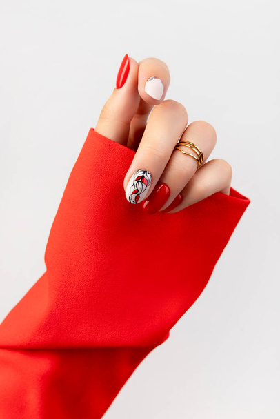 Mooie vrouwen hand met rode manicure op grijze achtergrond - Foto, afbeelding