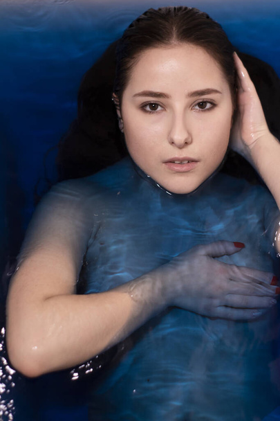 портрет привабливої брюнетки топлес в синій рідині. у ванні з кольоровою водою. потопаюча дівчина. копіювання простору
 - Фото, зображення