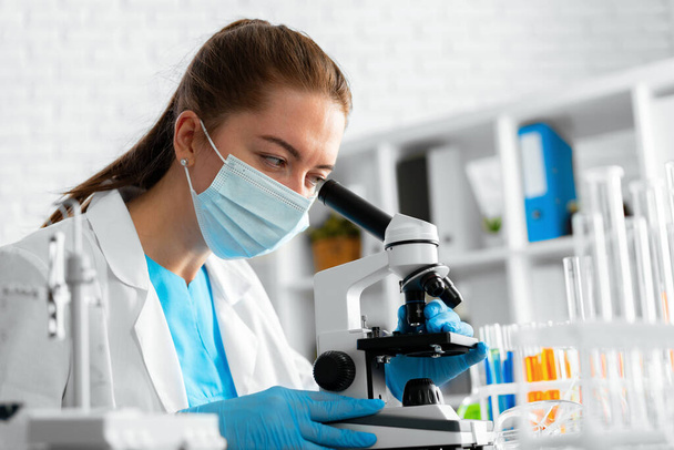 Young woman scientist using microscope in laboratory - Valokuva, kuva