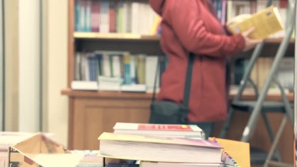 Woman in the library. She in blur, focus is in foreground - Footage, Video