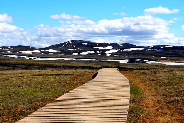 La vista del sentiero in legno che domina la montagna parzialmente innevata vicino a Krafla Lava Field, Myvatn, Islanda durante l'estate - Foto, immagini