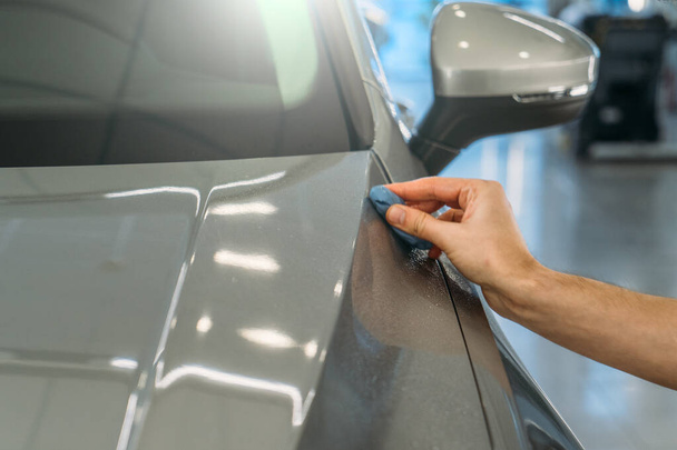 Werknemer hand schone auto lichaam met blauwe klei voor het reinigen voor het aanbrengen van beschermende laag of coating op auto. Detailconcept van de auto - Foto, afbeelding