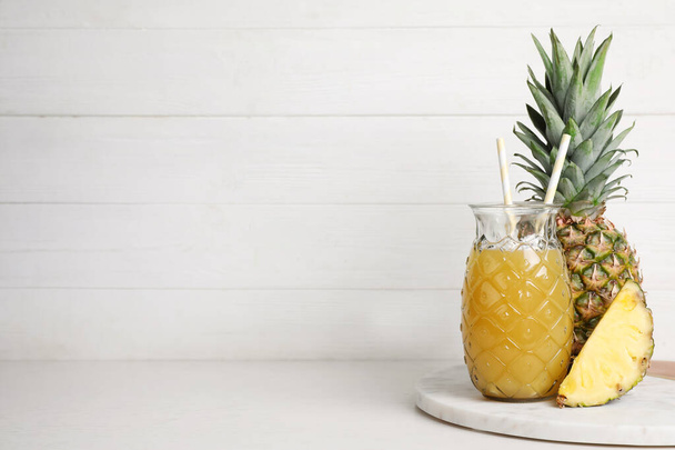 Freshly made pineapple juice on white table. Space for text - Zdjęcie, obraz