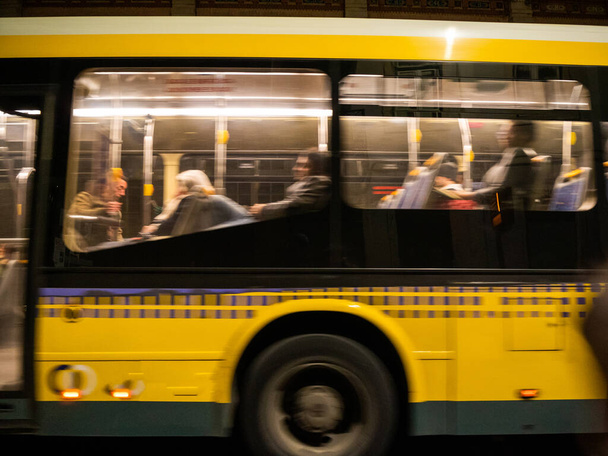 Rozmyty widok autobusu komunikacji miejskiej z sylwetkami podróżnych wewnątrz dojazdów - Zdjęcie, obraz